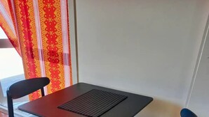 Un pequeño comedor con una mesa y dos sillas, un cortinaje estampado y suelo de baldosas.