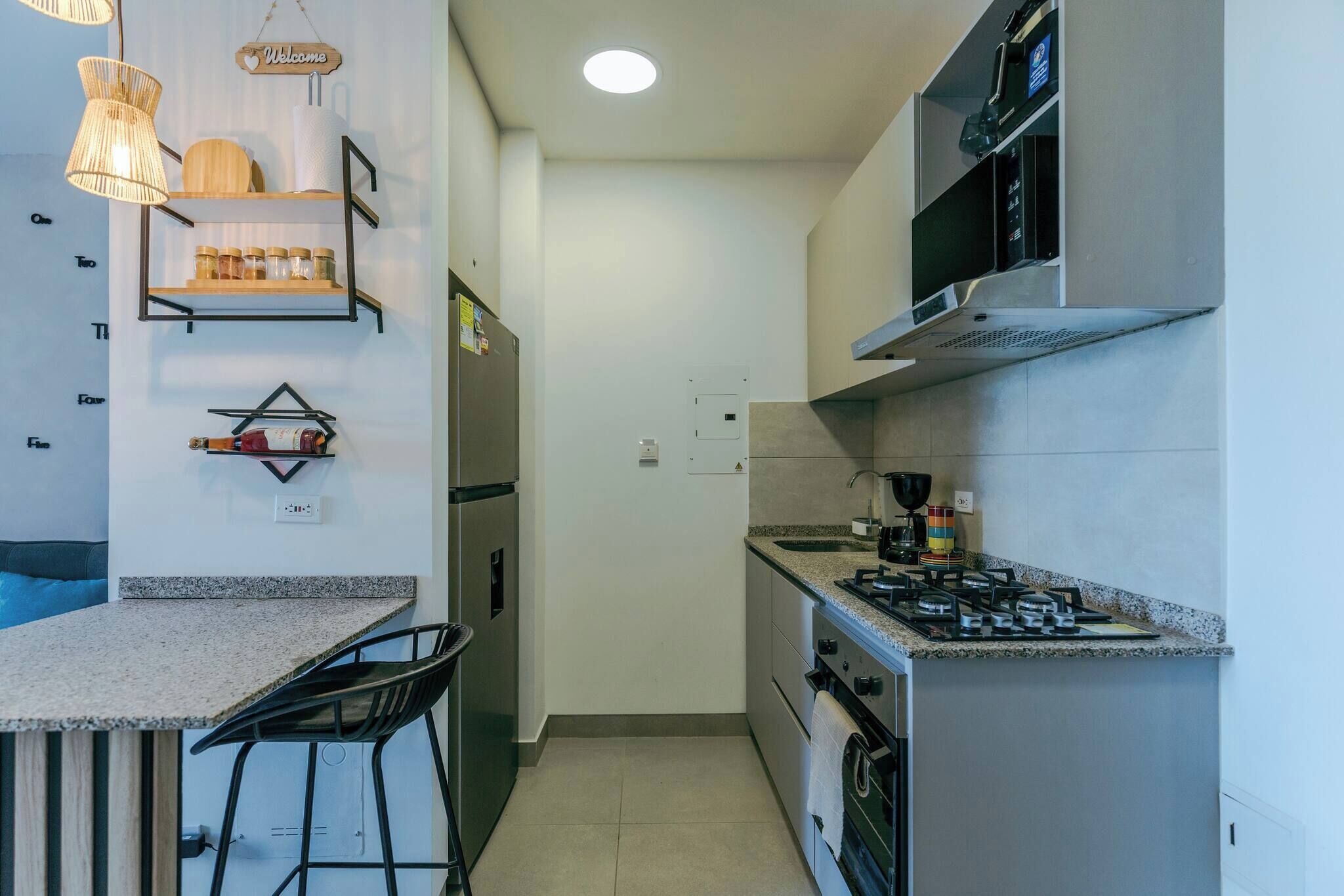 A compact kitchen with a gas stove, a sink, a refrigerator, and a bar area with stools.