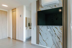 Ein modernes Hotelzimmer mit Marmorwand, einem an der Wand befestigten Flachbildfernseher und einer Holztür.