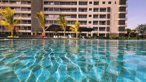 A swimming pool with clear water, surrounded by a building with multiple balconies and palm trees. - Modern Loft Beachfront,airport,wife Santa Marta (Santa Marta)