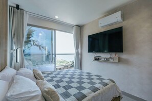 Ein Hotelzimmer mit Bett, Wandfernseher, Klimaanlage und Balkon mit Aussicht.