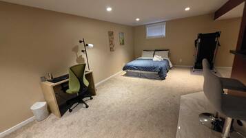 A bedroom with a bed, desk, chair, and exercise equipment.