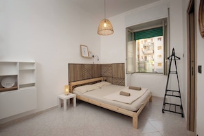 Una camera da letto con un letto, un comodino, una lampada, una finestra e una scala.