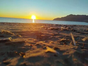 Una spiaggia con il sole che tramonta sull'acqua.
