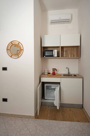Une cuisine compacte équipée d’un four à micro-ondes, d’un évier et d’un petit réfrigérateur.