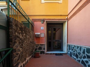 A stone wall, a metal railing, a door with a number plate, and a potted plant. - A cà du Piero by Interhome (Albisola)