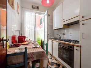 Een keuken met een gasfornuis, oven en een eettafel gedekt met borden en kopjes.