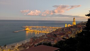 A coastal town with a prominent tower, a marina, and buildings with red-tiled roofs. - Fully furnished apartment, beaches, between Monaco and Menton (Roquebrune-Cap-Martin)