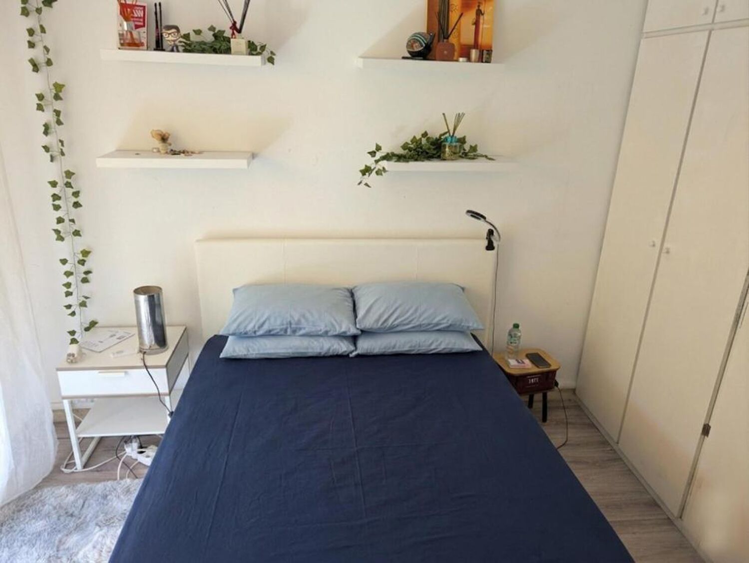 Ein Schlafzimmer mit Bett, Nachttisch, Lampe und Regalen mit Dekoration.