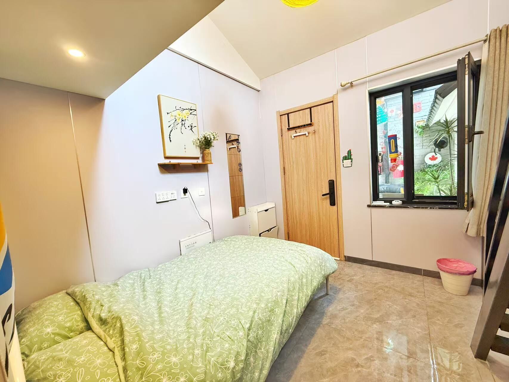 Une chambre à coucher avec un lit, une porte en bois, une fenêtre et une étagère fixée au mur.