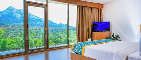 Une chambre d’hôtel avec un grand lit, une télévision et une vue sur les montagnes.