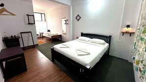 A bedroom with a bed, bedside table, and a desk. - Whispering Willows (Mudumalai)