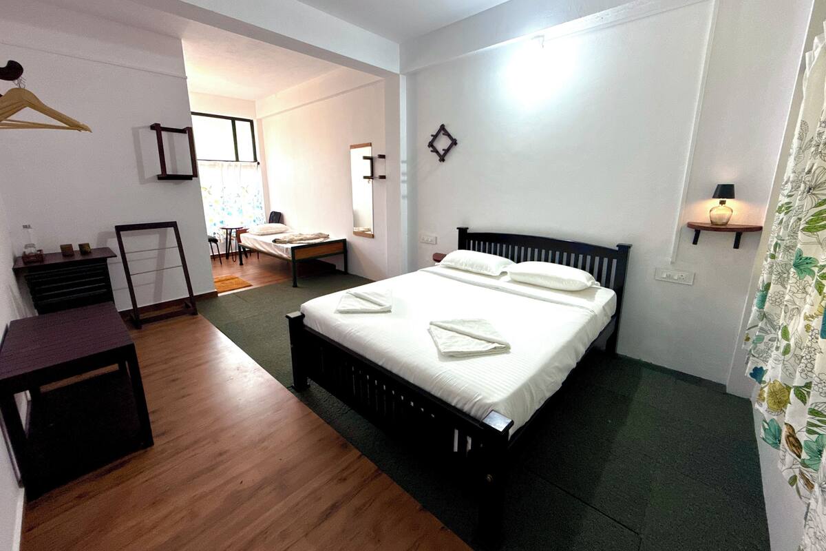 Un dormitorio con cama, mesita de noche y escritorio.