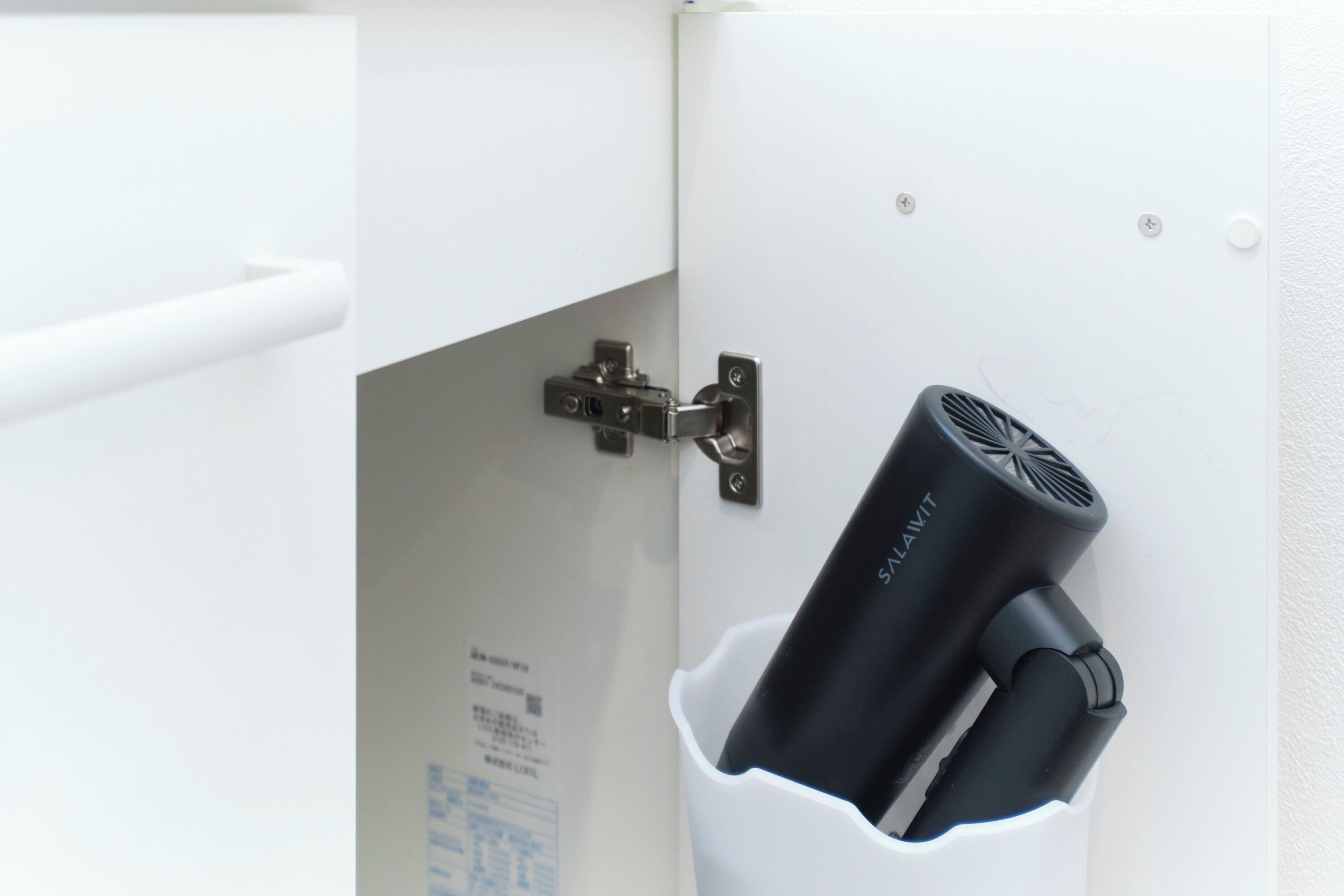 A white cabinet with a black device mounted on it.