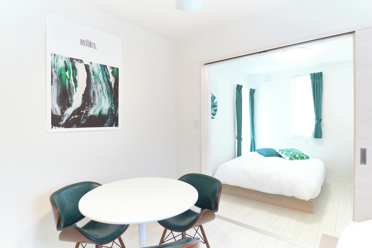 Quarto de hotel moderno com uma cama, uma mesa redonda, duas cadeiras e um pôster na parede.