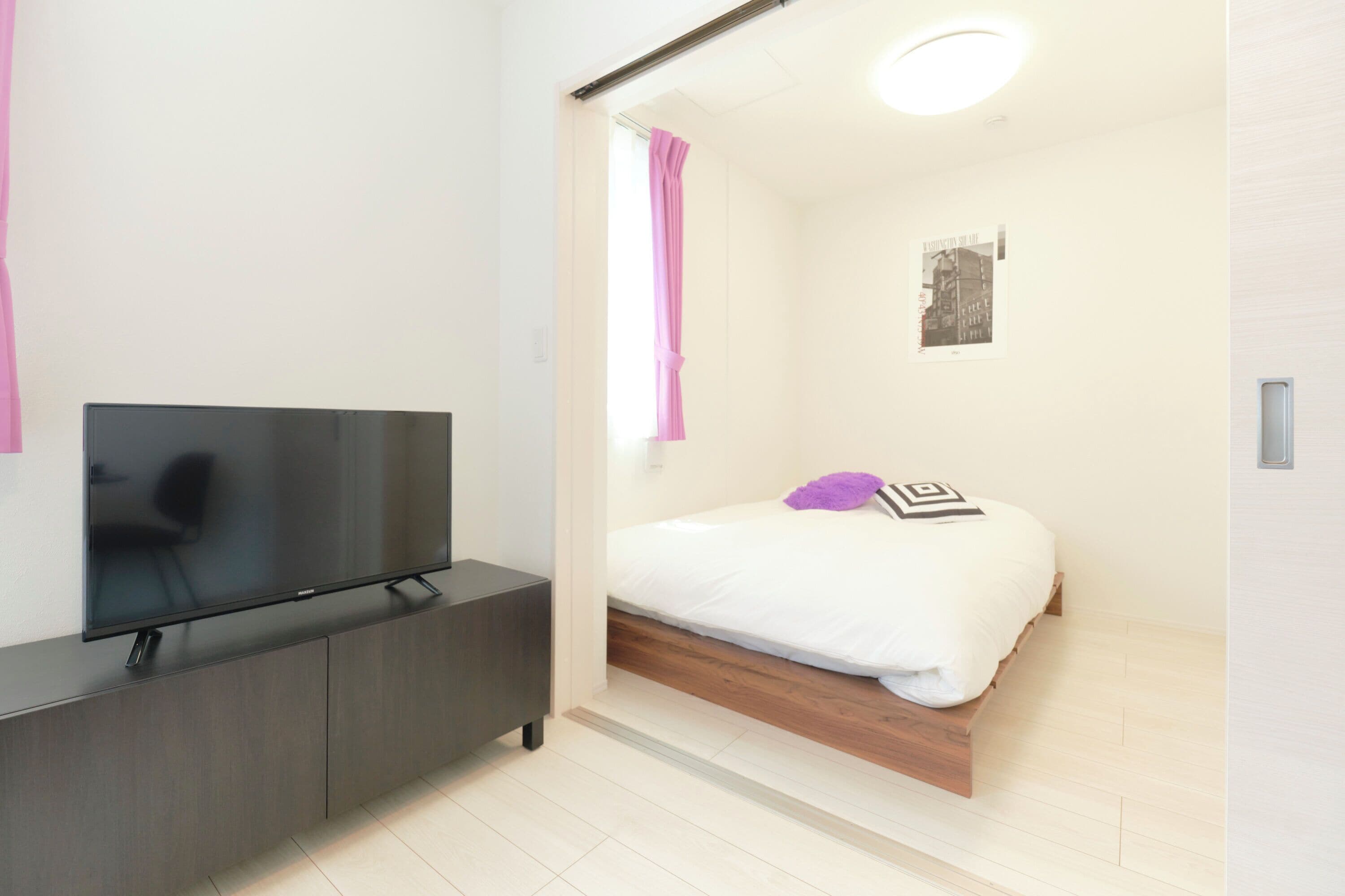 Une chambre à coucher moderne avec un lit, une télévision, une armoire en bois et une affiche accrochée au mur.