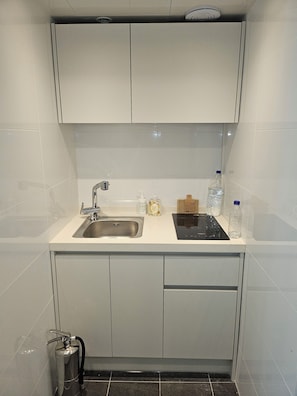 Una cocina compacta con un lavamanos, una estufa integrada y armarios.