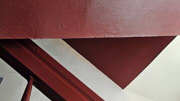 A close-up of a red metal staircase railing with a white wall in the background.