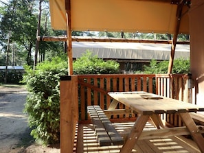 A wooden deck with a picnic table and benches, surrounded by greenery and a covered area. - Holiday Home in Otterlo With Terrace (Otterlo)