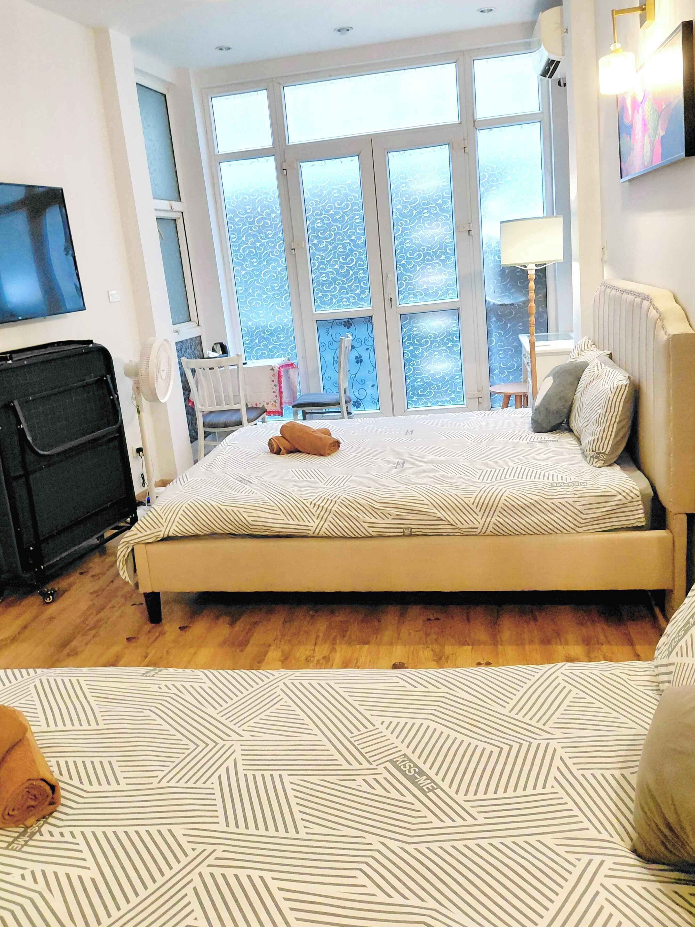 Un dormitorio con una cama grande, televisor, escritorio y ventana con vistas.
