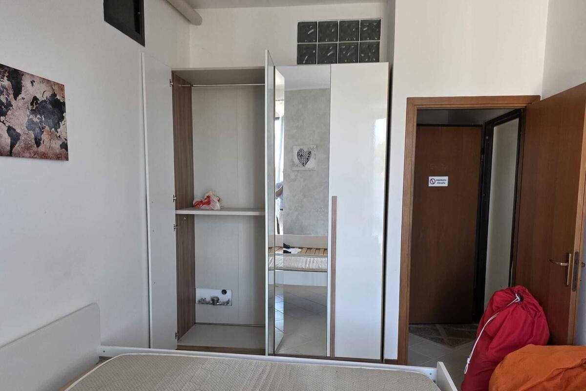 Une pièce comprenant un lit, une armoire, un miroir et une porte.