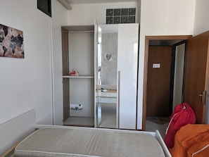 Een kamer met een bed, een kledingkast, een spiegel en een deur.