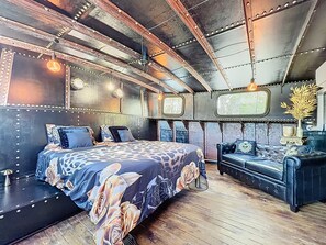 A room with a bed, a sofa, and a decorative vase.