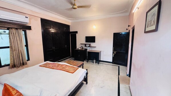 A bedroom with a bed, a desk, a television, and a wardrobe. - Moti Mahal Muroli (Udaipur)