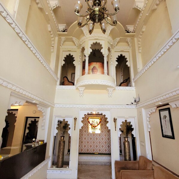 A grand interior with ornate arches, a chandelier, and a central shrine. - Moti Mahal Muroli (Udaipur)