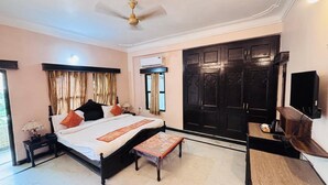 Un dormitorio con cama, mesita de noche, lámpara, ventana con cortinas, armario y televisor.