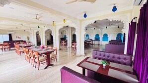 Un comedor espacioso con techos altos, candelabros y arcos tradicionales.