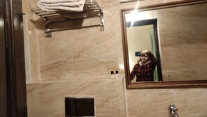 Un baño con pared de mármol, toallero, espejo y lavabo.