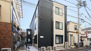 A multi-story building with external air conditioning units, a pedestrian crossing sign, and a bicycle parked outside.