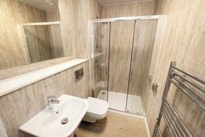 A modern bathroom with a glass-enclosed shower, a white sink, and a mirror. - Spacious City-Centre Home with Garden (Edinburgh)