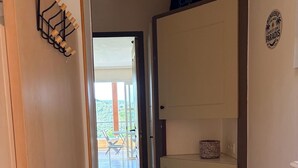 Ein Korridor mit einer Holztür, einem weißen Schrank und Blick auf einen Balkon mit Gartenmöbeln.