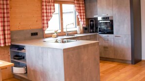 Une cuisine moderne avec des poutres en bois, un îlot central et des appareils électroménagers intégrés.