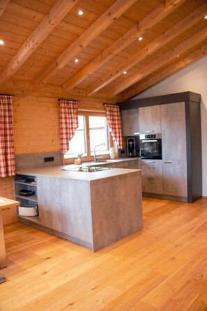 Una cucina moderna con travi in legno, un'isola centrale ed elettrodomestici integrati.