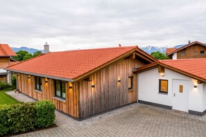 Una casa moderna con tetto in tegole rosse, rivestimento in legno e vialetto lastricato.
