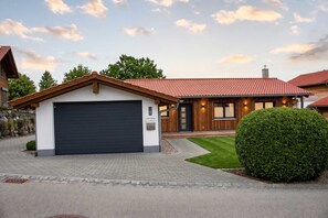 Et moderne hus med garage, velplejet græsplæne og en stor busk.