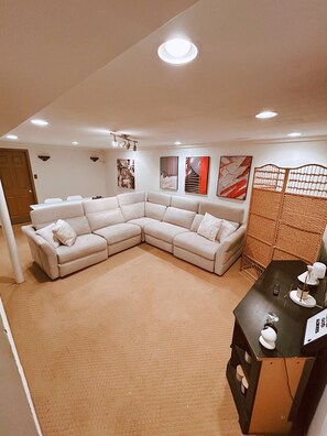 Een woonkamer met een hoekbank, een eettafel met stoelen en een decoratieve scheidingswand.