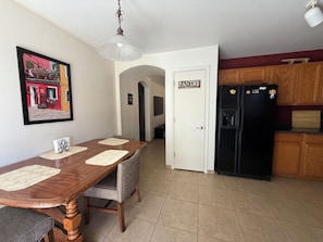 A dining area with a wooden table and chairs, a black refrigerator, and a pantry door.
