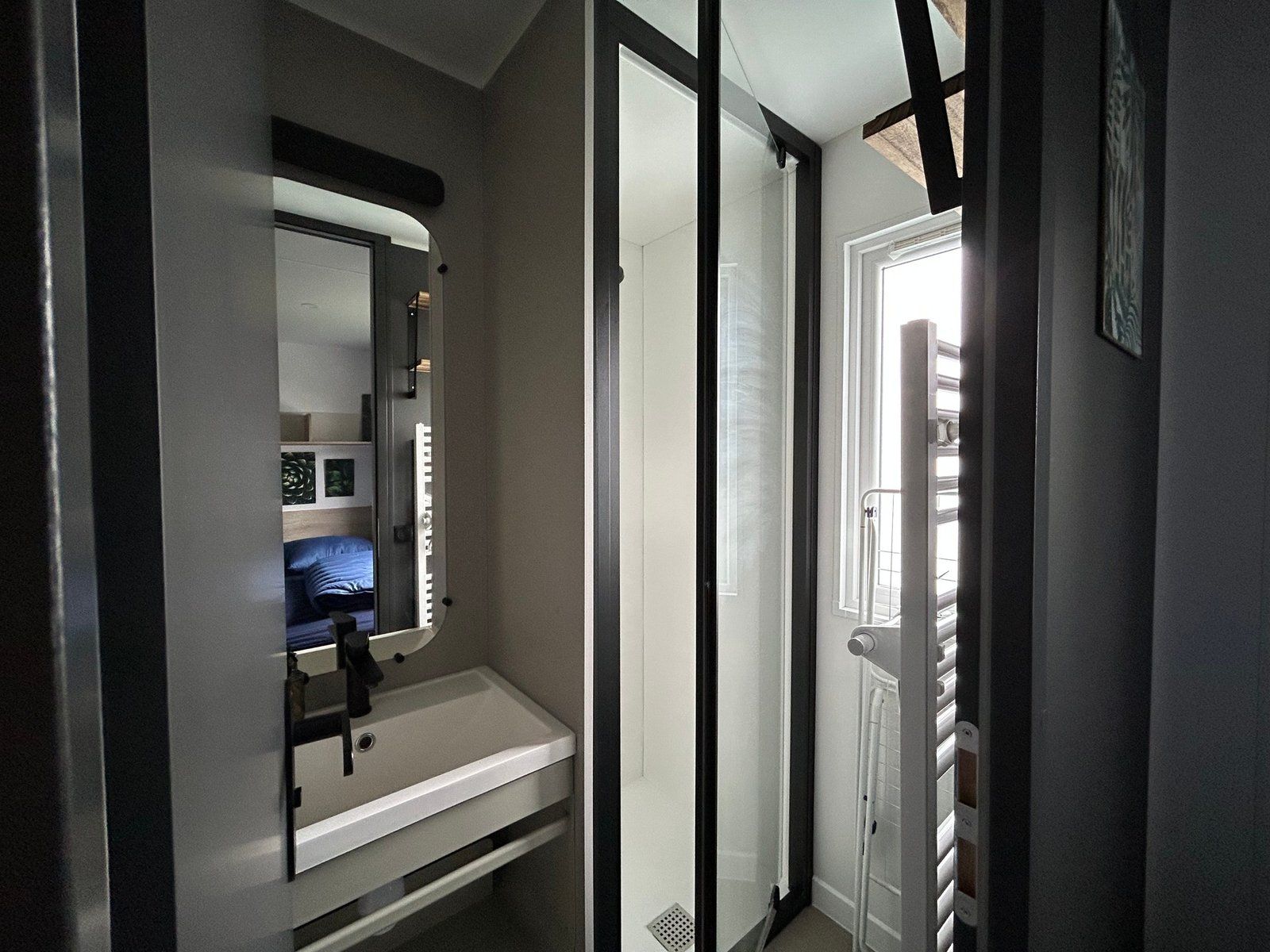 Un baño con un lavamanos blanco, un espejo y una puerta que da a otra habitación.