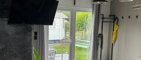 A room with a television, a bench outside, and a door leading to a patio.