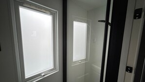 Une pièce avec deux fenêtres, une porte et un radiateur.