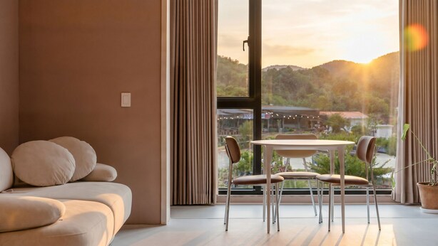 Una sala de estar moderna con un sofá, una mesa de comedor con sillas y un ventanal con cortinas.