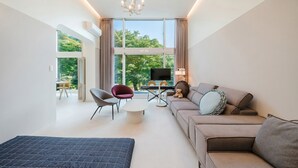 Una sala de estar moderna con un sofá, sillas, una mesa de centro, un televisor y un balcón con vistas.