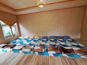 Ein Zimmer mit einem großen Bett, Holzboden, einem Fenster mit Vorhängen und einer Deckenleuchte.