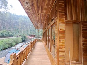 Eine Holzterrasse mit Blick auf bewaldetes Gebiet und einen Fluss.