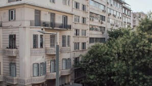 A multi-story building with balconies, a street in front, and a pedestrian crossing. - Eden suite | Downtown Athens (Athina)
