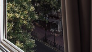 A view through a window of a multi-story building with balconies, trees, and a clear sky. - Eden suite | Downtown Athens (Athina)
